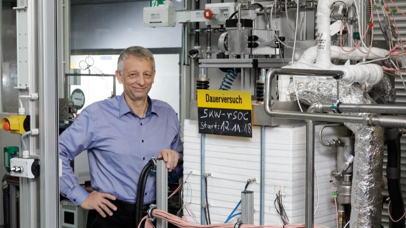 Prof. Blum zeigt am Forschungszentrum Jülich das Herzstück der reversiblen Hochtemperaturanlage:  Sie kann nicht nur aus Wasserstoff Strom erzeugen,  sondern auch umgekehrt aus Strom und Wasserdampf Wasserstoff produzieren.