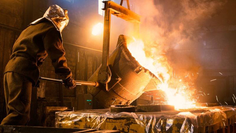 Arbeiter kontrolliert Metallschmelze in Gießerei