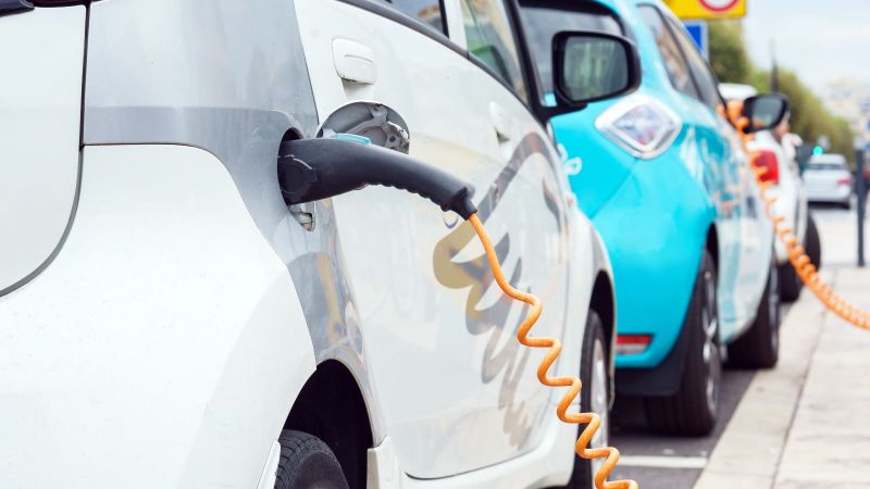 Zwei Elektrofahrzeuge stehen jeweils an einer Ladesäule und tanken Strom.