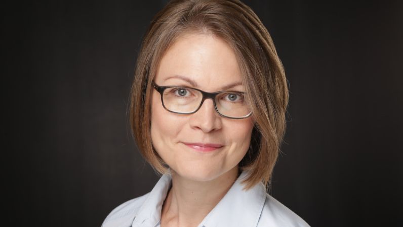 Portraitbild von Anna Leippert. Sie hat dunkelblonde lange Haare und ein freundliches Lächeln.