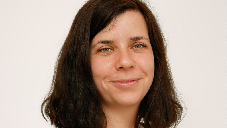 Portraitbild von Christine Krüger. Sie hat schulterlange dunkle Haare und blaue Augen.