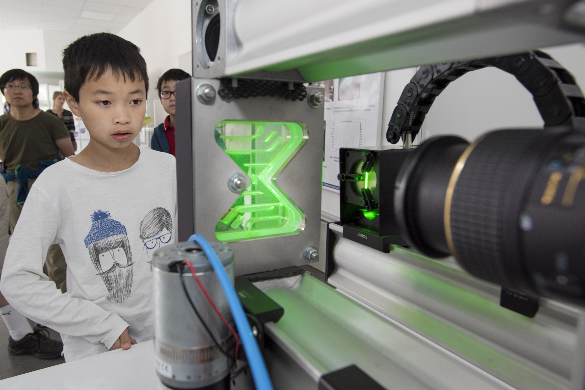 Ein Junge blickt fasziniert auf eine grün leuchtende Laser-Gerätschaft. 