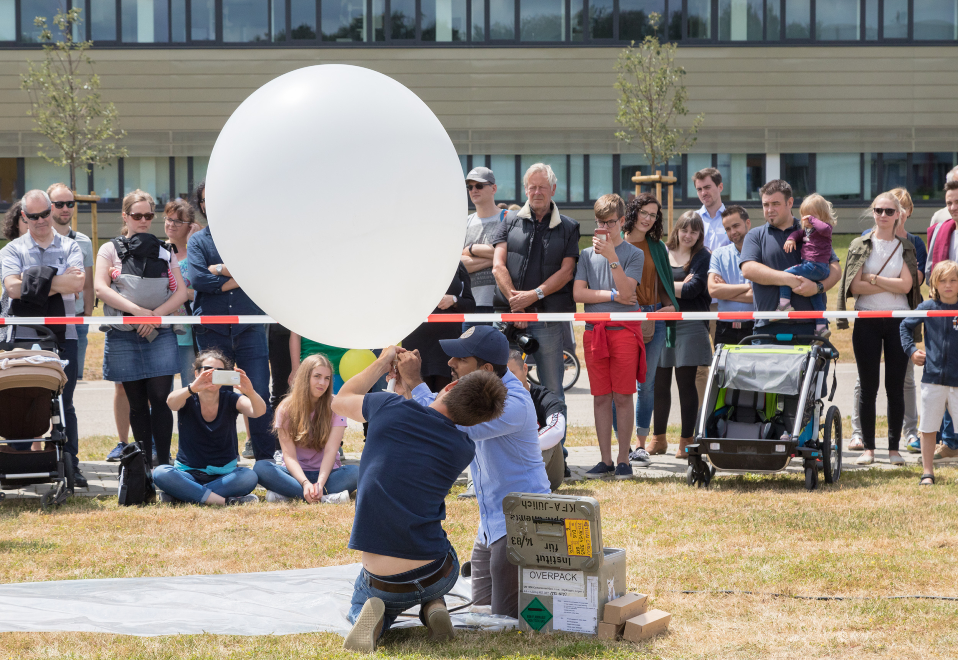 Zwei Wissenschaftler treffen Vorbereitungen, um einen Wetterballon steigen zu lassen. Sie werden gespannt von den umstehenden Besucherinnen und Besuchern beobachtet.