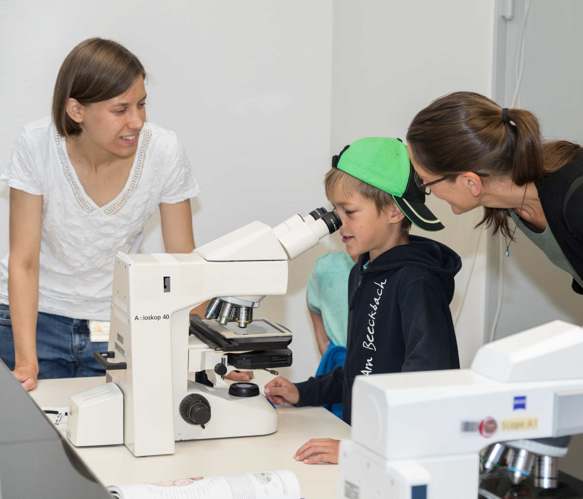 Eine Wissenschaftlerin begeistert Kinder für den Blick ins Mikroskop.